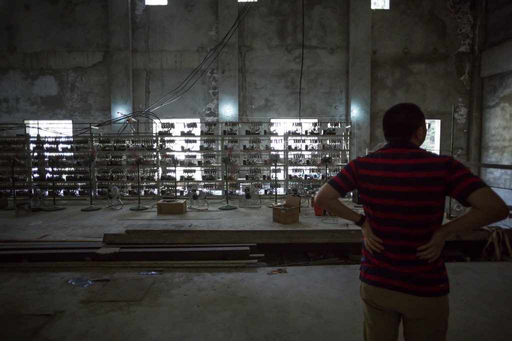 Ryan Xu, chief strategy officer and co-founder of Bitcoin Group Limited, shows off mining equipment inside his company's bitcoin mine near Kongyuxiang, Sichuan, China.