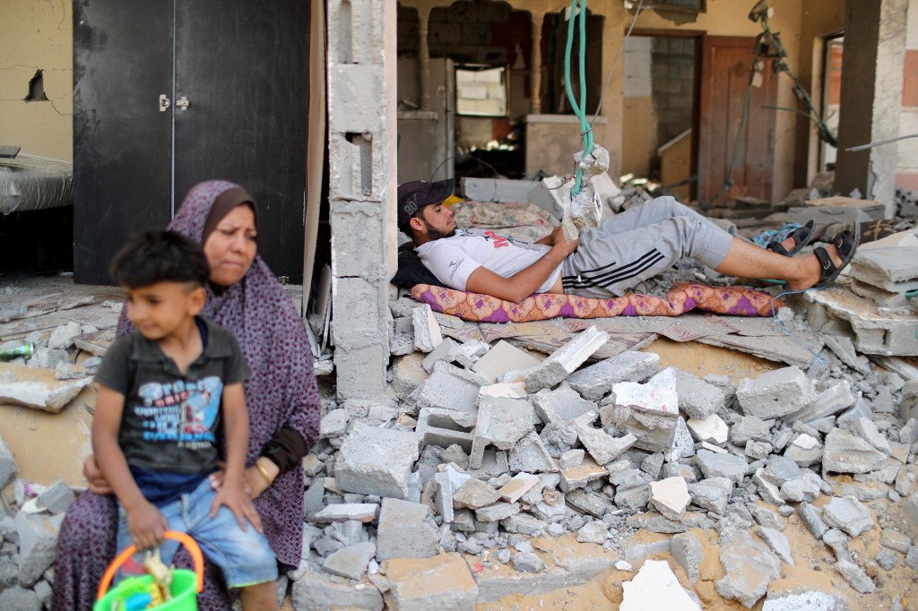 A Palestinian man rests amidst the debris after returning to his damaged house following Israel- Hamas truce, in Beit Hanoun.