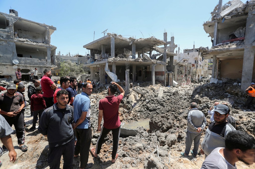 Palestinians gather at the site of destroyed houses in the aftermath of Israeli air and artillery strikes as cross-border violence.