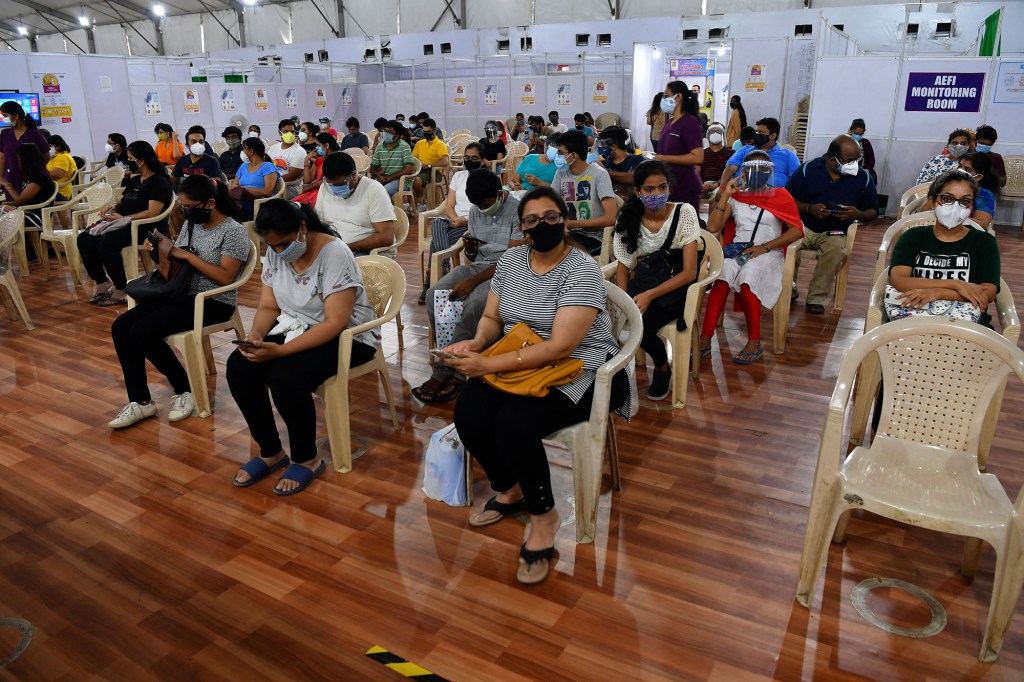 People sit in an observation area after getting inoculated with a dose of the Covishield vaccine.