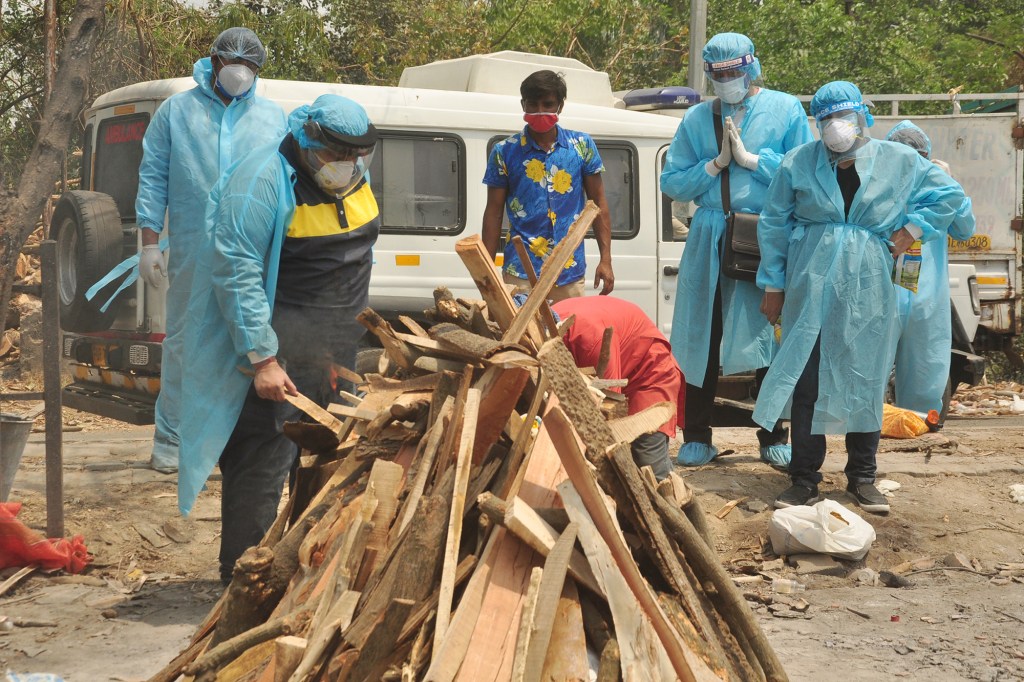 A COVID-19 victim's family members prepare the funeral pyre.