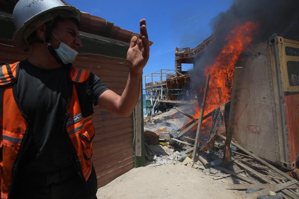 A Palestinian firefighter rushes to extinguish a burning shack following an Israeli naval bombardment around the port of Gaza City on May 17, 2021.