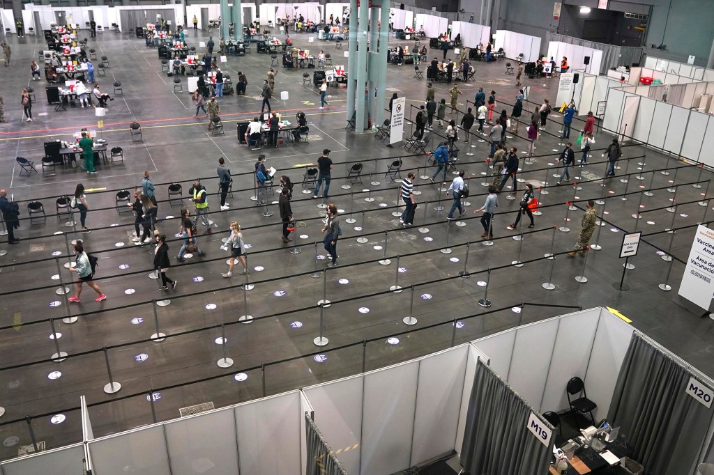 People stand in line at the Jacob K. Javits Convention Center, Tuesday, April 6, 2021