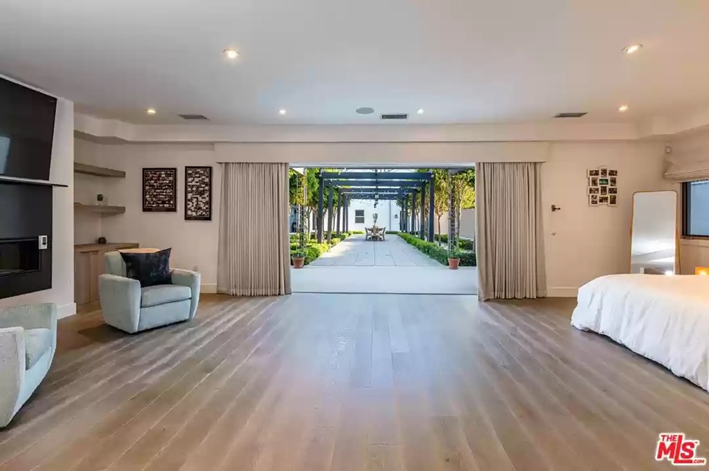 On the main floor, the primary bedroom suite flows seamlessly into the trellised patio dining area.