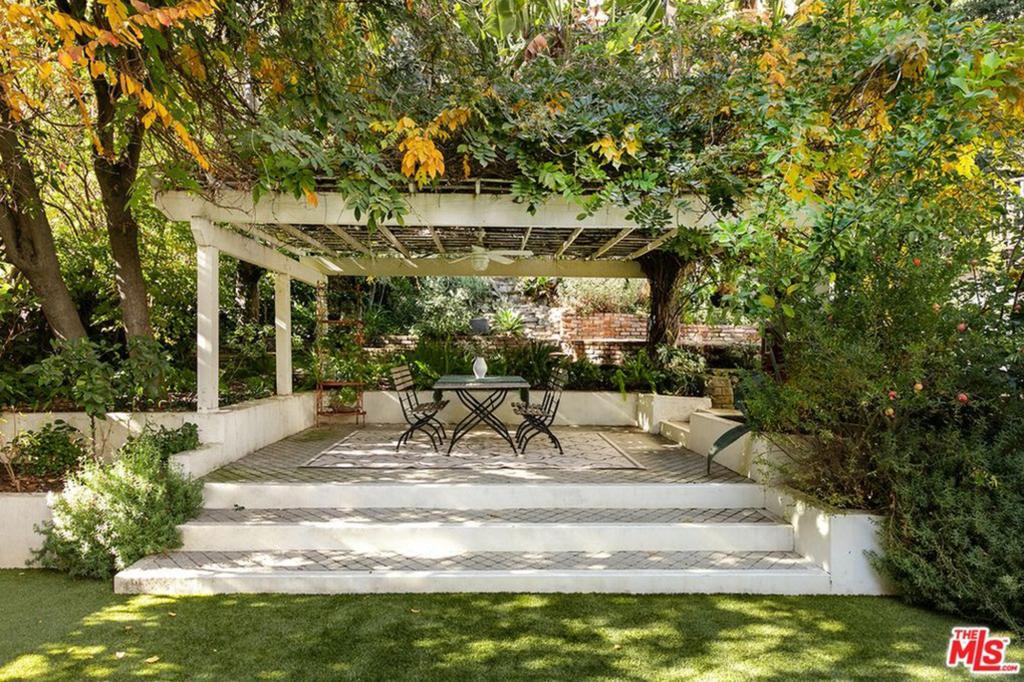 A vine-covered pergola creates a gracious outdoor living and dining area.