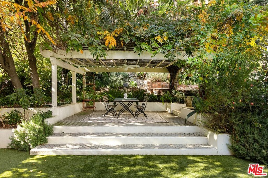 A vine-covered pergola creates a gracious outdoor living and dining area. 