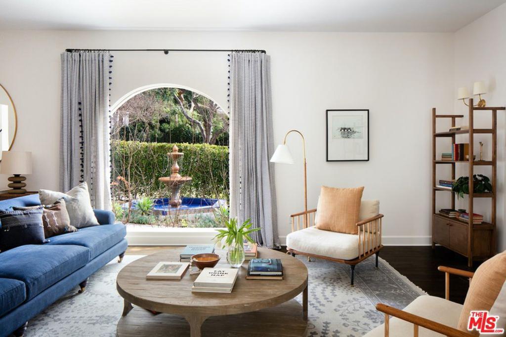 To the left of the foyer, a living room boasts a fireplace and views of the front fountain through a huge arched window.