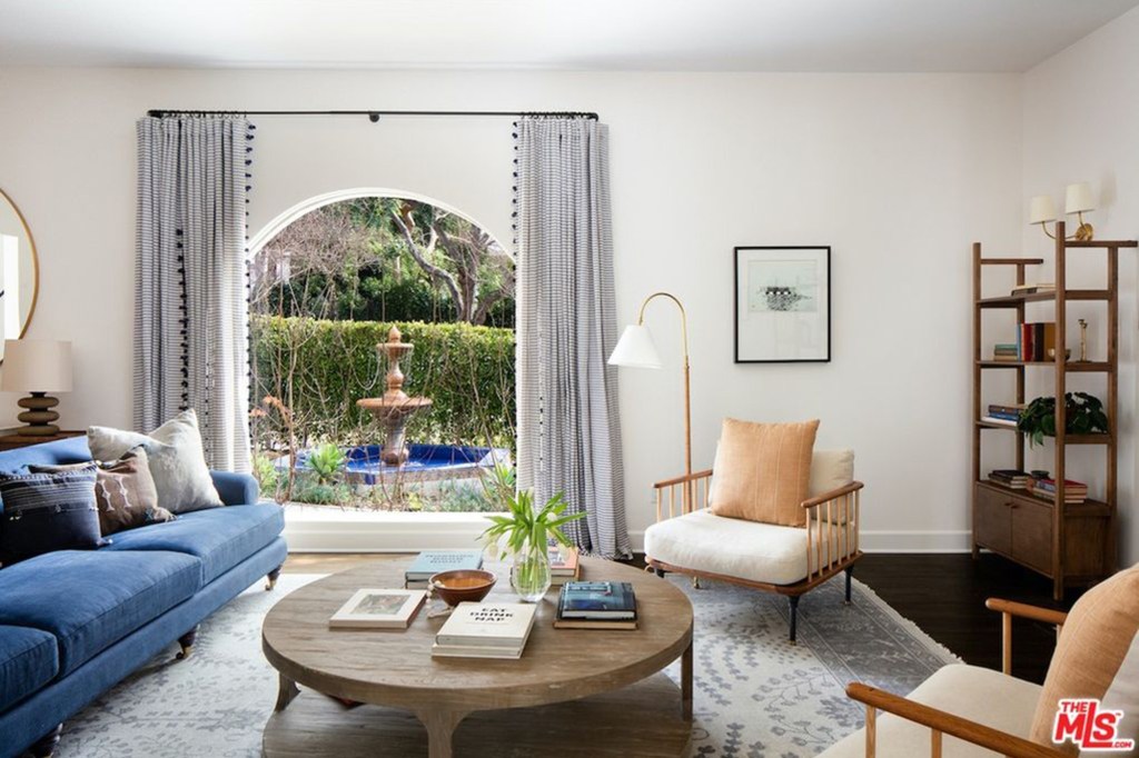 To the left of the foyer, a living room boasts a fireplace and views of the front fountain through a huge arched window. 