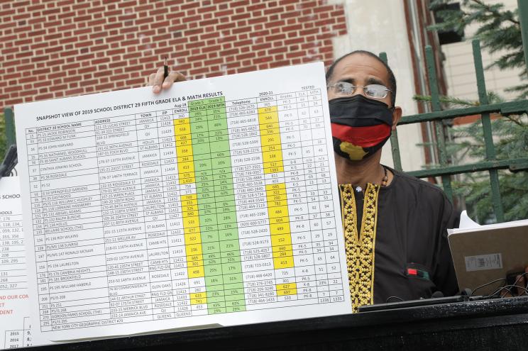 Activist Raymond Dugue shows off poor state math proficiency test score results reported in Queens District 29.