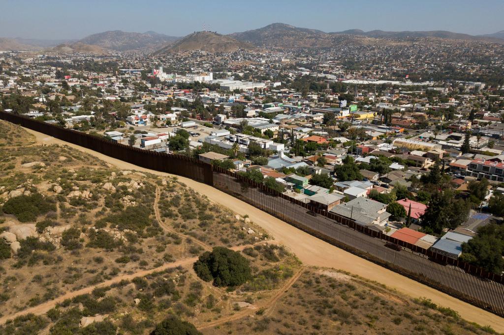 An aerial image shows steel bollard-style border wall barriers standing along the US-Mexico border between San Diego County and the Mexican city of Tecate, Baja California, (R) on May 10, 2021, in Tecate, California.