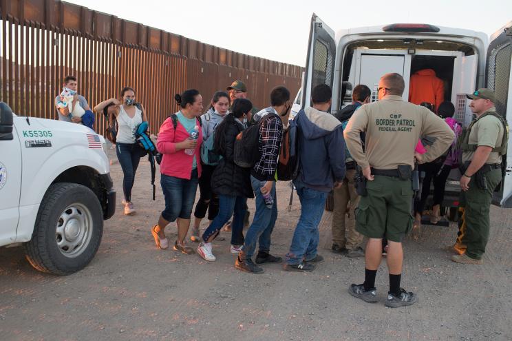 Border patrol agents escort migrants into vans after arresting them near Yuma, Arizona on April 29, 2021.