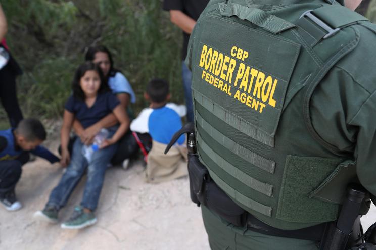 Central American asylum seekers wait as U.S. Border Patrol agents take them into custody.