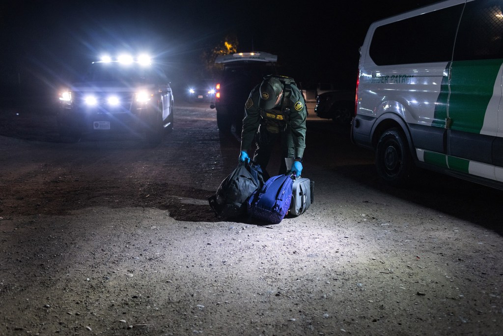 A U.S. Border Patrol agent collects backpacks from Venezuelan immigrants after taking them into custody.