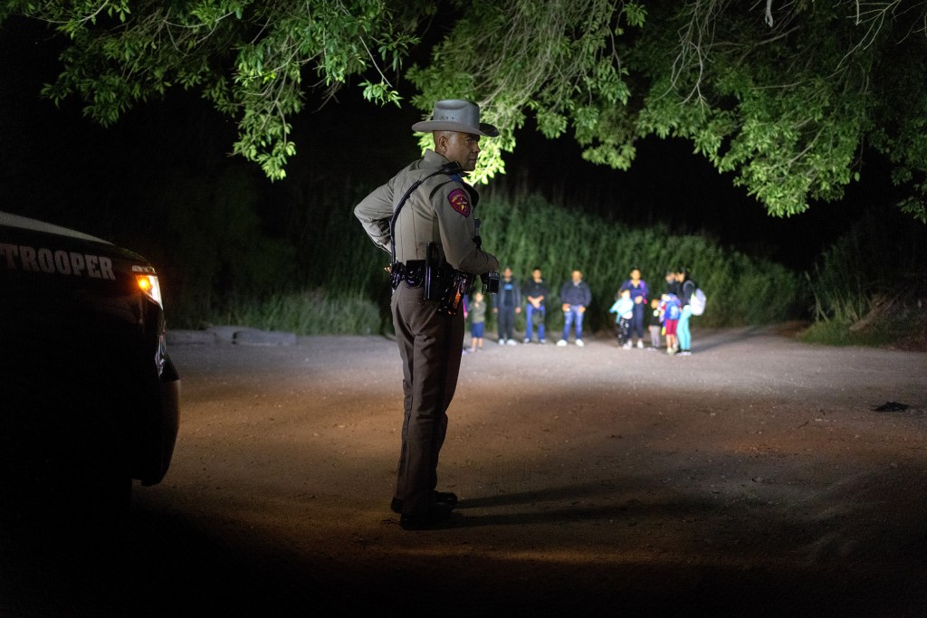 A Texas state trooper watches over Venezuelan immigrants as they  wait to be taken into custody by U.S. Border Patrol agents.