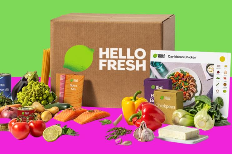 A HelloFresh meal kit box on a green and pink backdrop.