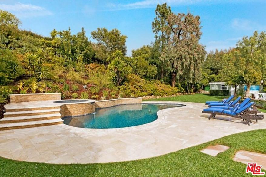 The hot tub is accessible up a few steps in the stone patio.