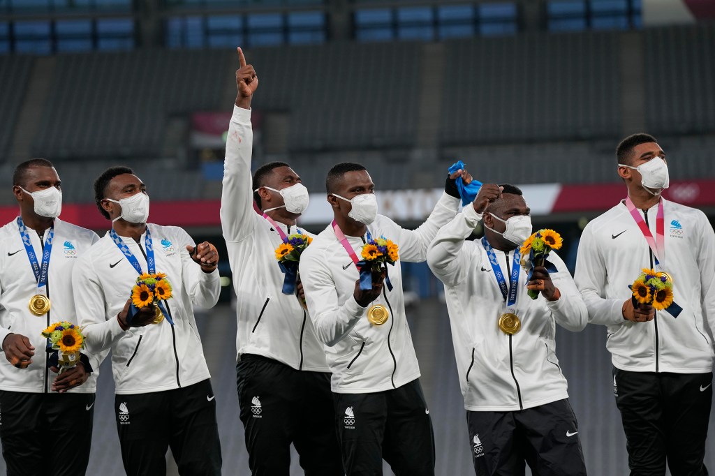 Fiji's players wear face masks as they celebrate on the podium with their gold medals in men's rugby sevens at the 2020 Summer Olympics.