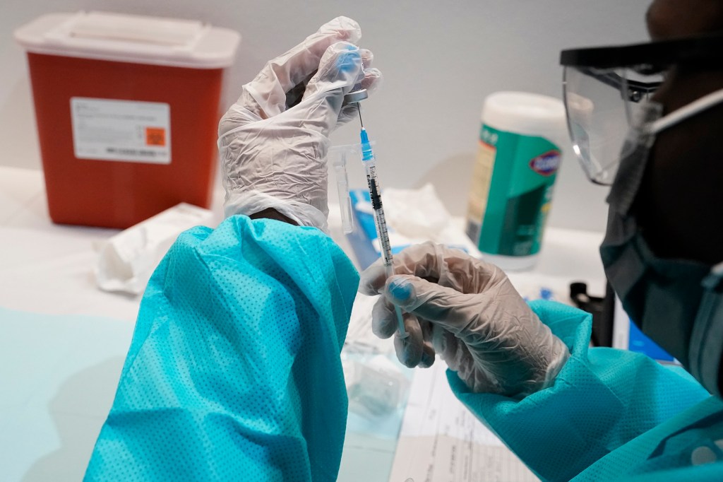 A health care worker fills a syringe with the Pfizer COVID-19 vaccine, Thursday, July 22, 2021, at the American Museum of Natural History in New York. The museum moved their vaccination site from the Hall of Ocean Life where the famous 94-foot-long model of a blue whale is hanging from the ceiling to a smaller adjacent gallery. New York City is closing the big vaccination sites to focus on areas with low vaccination rates.