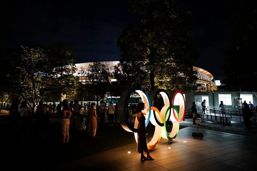 People take pictures with the Olympic rings outside the Olympic Stadium during the 2020 Summer Olympics, Saturday, July 31, 2021, in Tokyo, Japan.