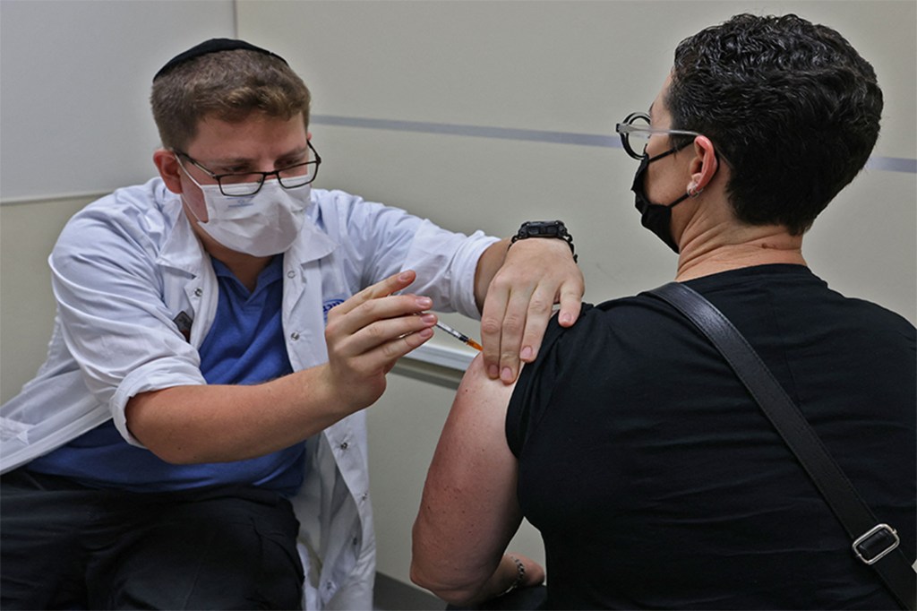 A man gives a person a COVID-19 vaccine.