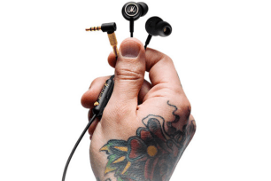 A tattooed hand holding black headphones