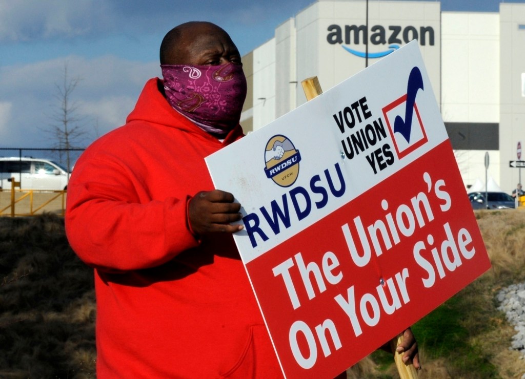 A member of the Retail, Wholesale and Department Store Union holds a sign outside an Amazon facility where labor is trying to organize workers in Bessemer, Alabama.