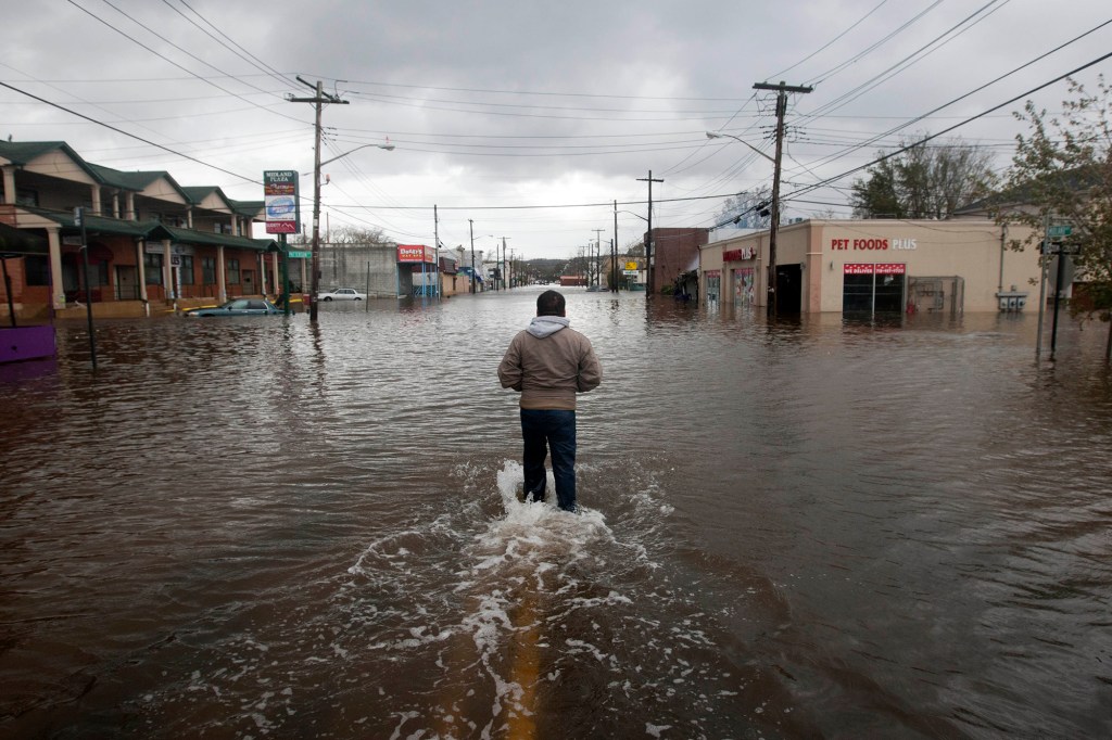 A man walking through flood waters in Midland Beach, Staten Island after Hurricane Sandy on October 30, 2021.