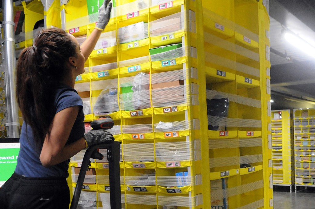 A female Amzon worker reaching up to get pull out a storage drawer.