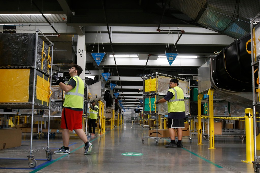 Two Amazon workers moving boxes wheels.