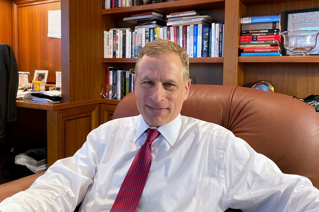 Robert Kaplan sitting in a leather office chair behind a desk with bookcases behind him