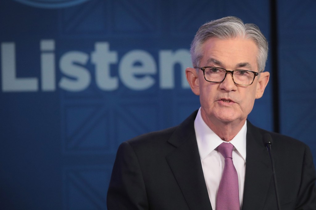 Jerome Powell on a stage with the word LISTEN, in caps, in the background