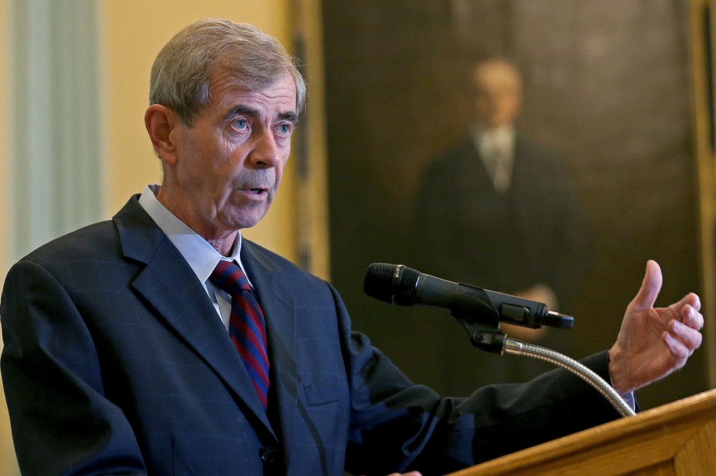 William Galvin standing in front of a microphone at a podium