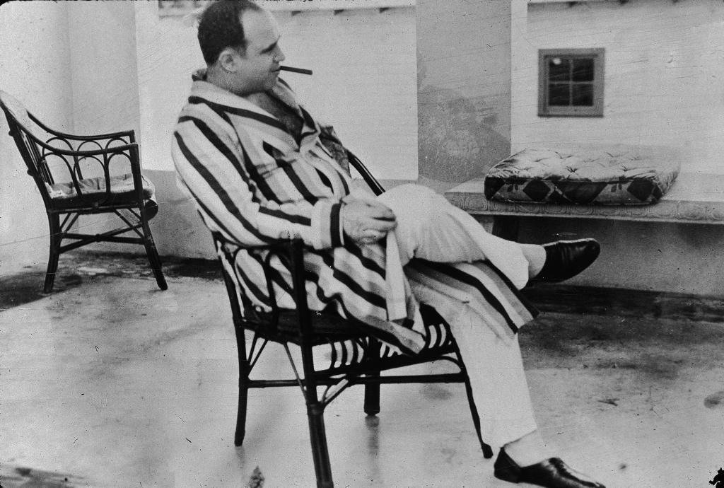 American gangster Al Capone, who inspired the film "Scarface" relaxes in his vacation home im Miami, Florida in 1930. Capone smokes a cigar and wears a striped dressing gown and slippers.