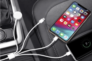 An array of white charging cables in a car and one plugged into an iPhone