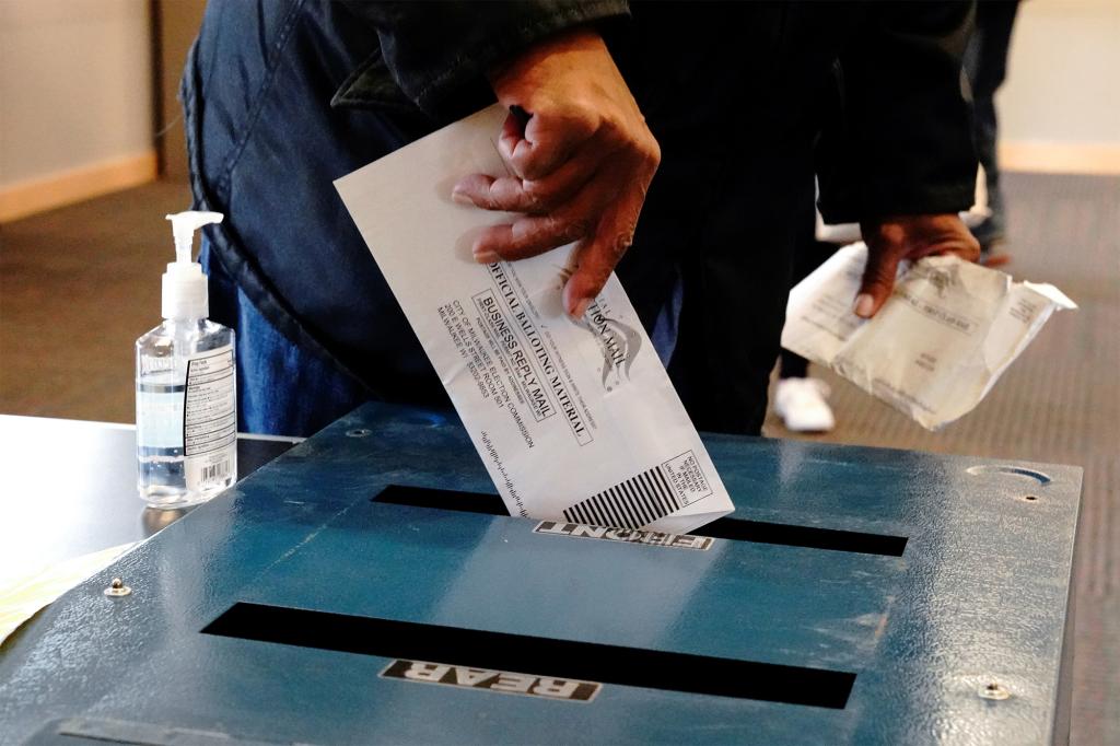 A voter casts his ballot next to a bottle of hand sanitizer.