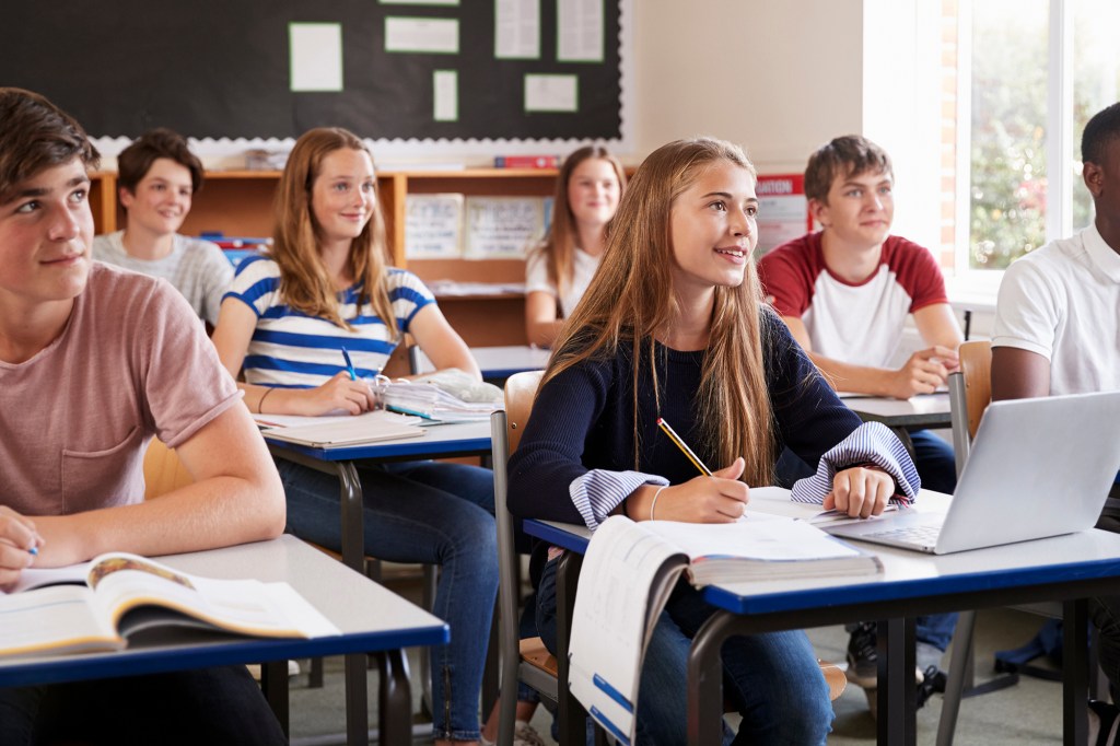 Students Listening To Female Teacher In Classroom