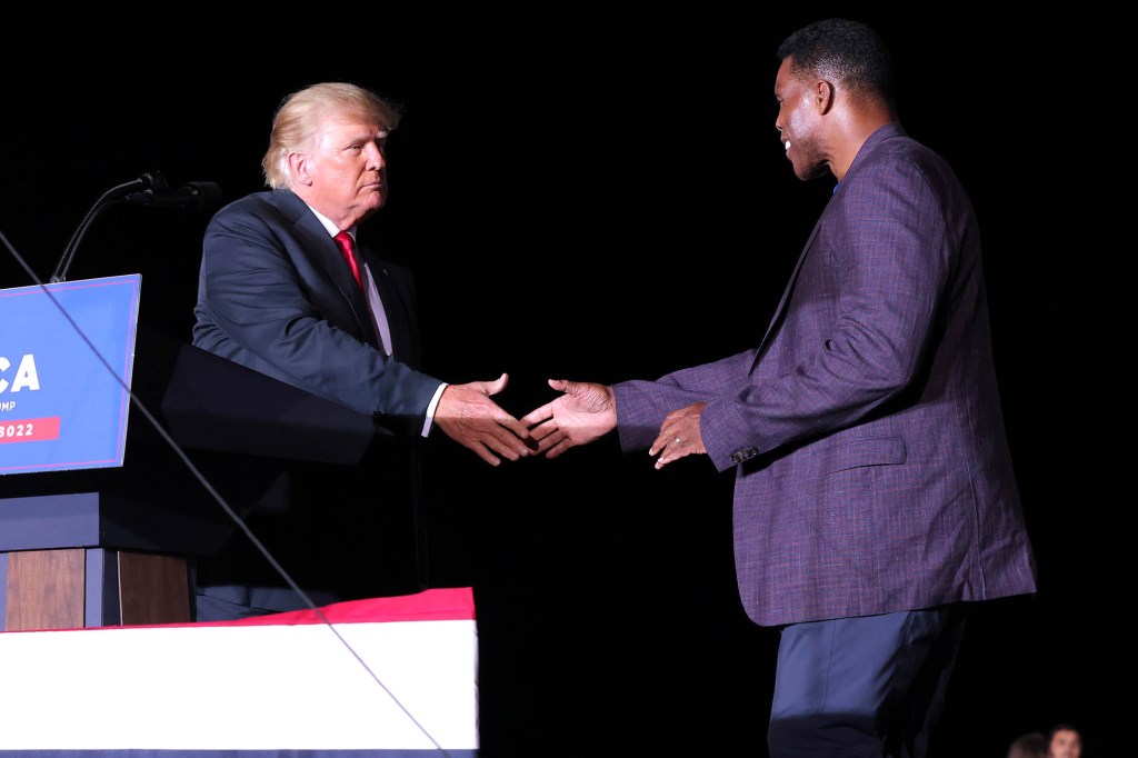 Former college football star and current senatorial candidate Herschel Walker shakes hands with former U.S. President Donald Trump