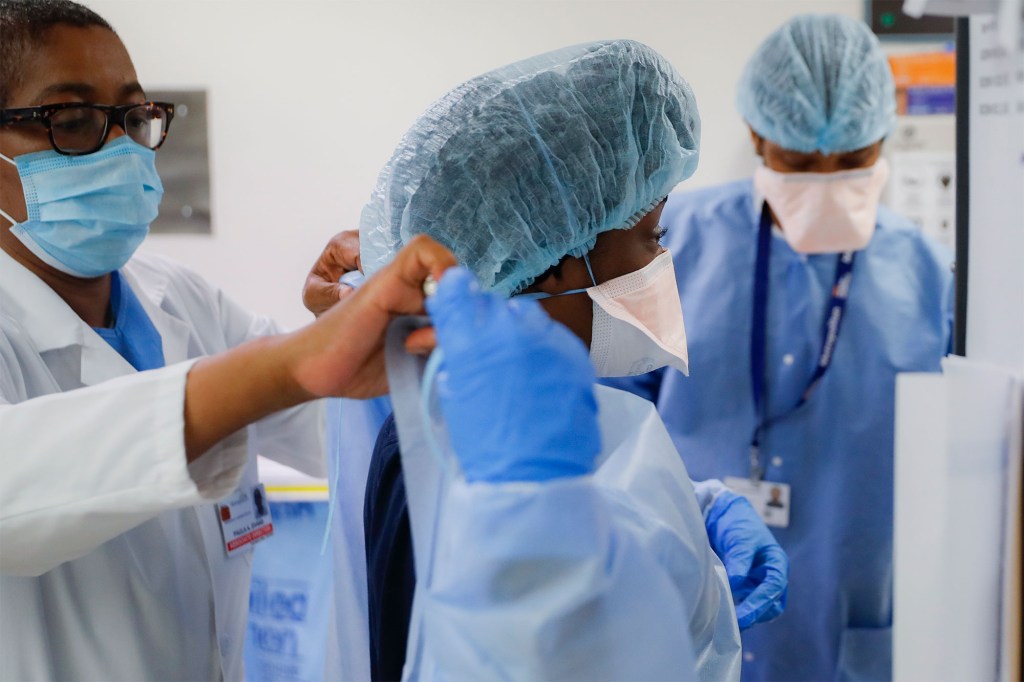 Medical personnel adjust their personal protective equipment while working in the emergency department at NYC Health + Hospitals Metropolitan, May 27, 2020