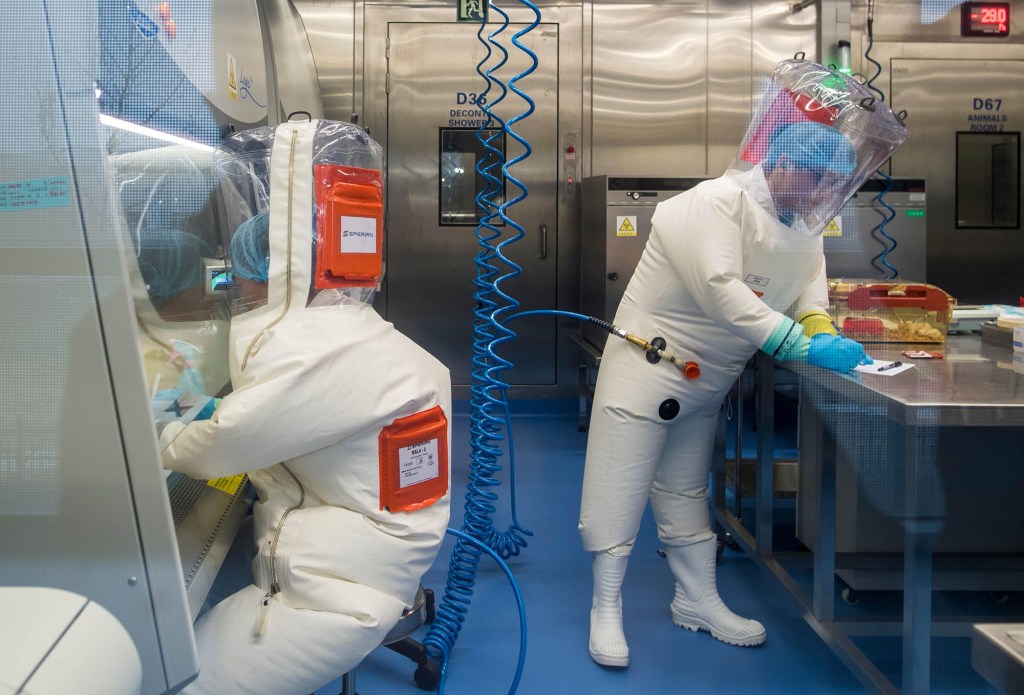 Workers next to a cage with mice (R) inside the P4 laboratory in Wuhan, the capital of China's Hubei province.