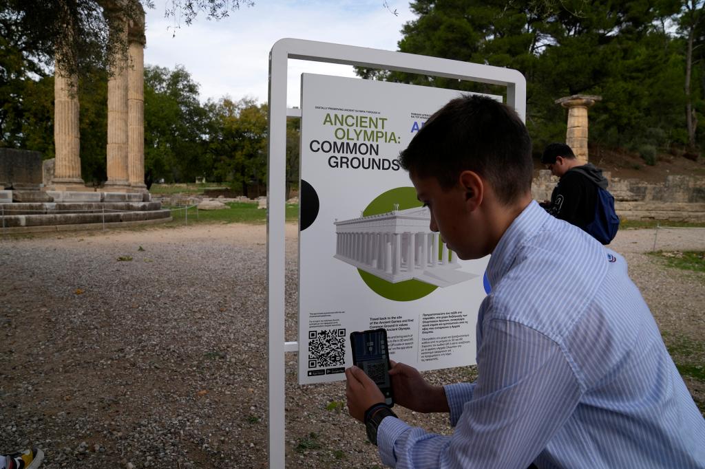 A school student scans a QR code at the ancient site of Olympia, southwestern Greece, Wednesday, Nov. 10, 2021.