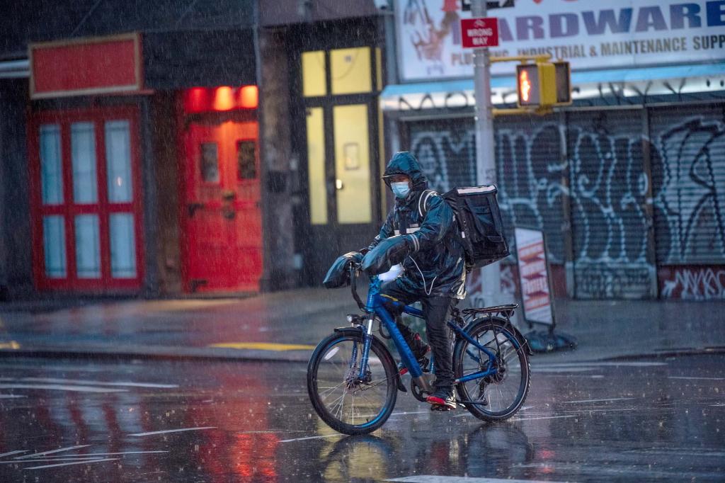 A food delivery worker riding a bicycle in the rain.