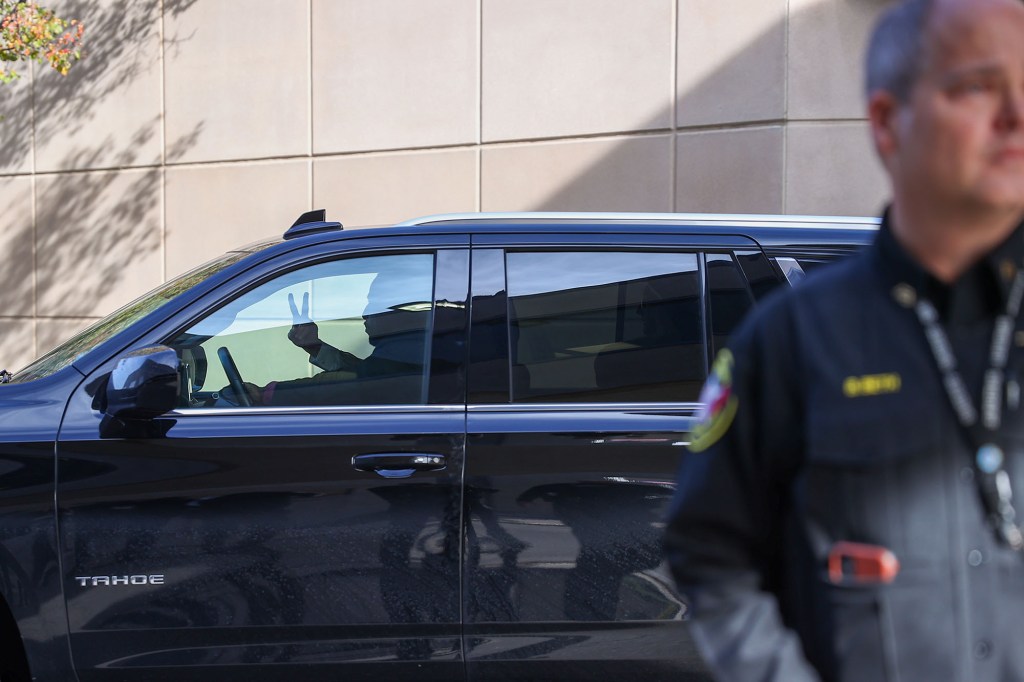 Kyle Rittenhouse's attorney flashes a peace sign as he leaves the courthouse with Rittenhouse in tow.