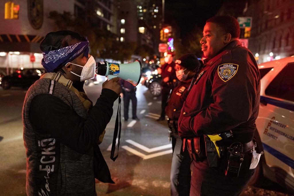 A demonstrator confronts an NYPD officer while marching on the street during a protest against the Kyle Rittenhouse not-guilty verdict near the Barclays Center in New York on November 19, 2021.