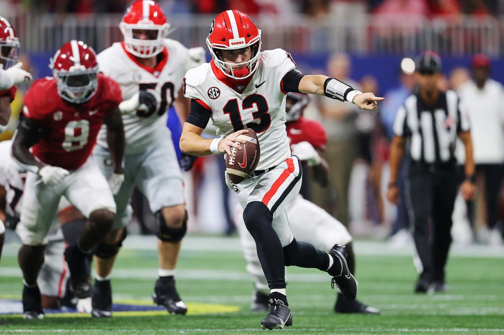 Stetson Bennett #13 of the Georgia Bulldogs carries the ball against the Alabama Crimson Tide during the third quarter of the SEC Championship game against the at Mercedes-Benz Stadium on December 04, 2021 in Atlanta, Georgia.