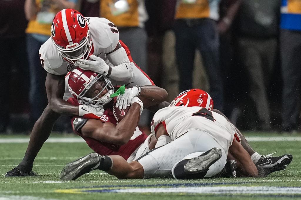 Alabama wide receiver John Metchie III (8) is tackled by Georgia defensive back Derion Kendrick (11) and linebacker Nolan Smith (4) during the first half at Mercedes-Benz Stadium.