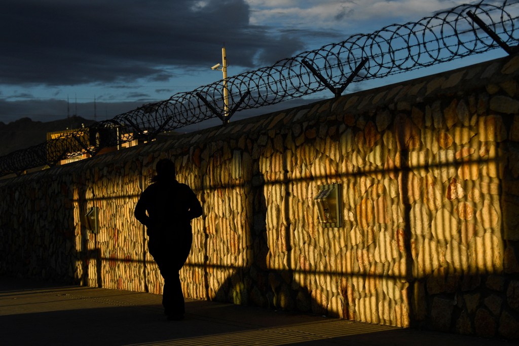 People walk along a fence after crossing the border from Mexico at the US Customs and Border Protection Paso del Norte Port of Entry along the US-Mexico border between Texas and Chihuahua state on December 9, 2021 in El Paso, Texas. 