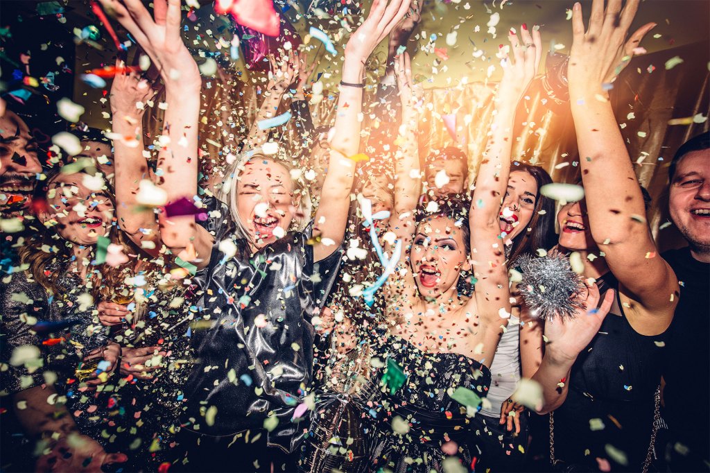 Confetti falling over a smiling group of people on a dance floor of a nightclub