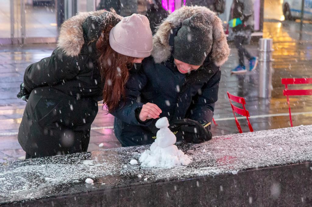 People in Times Square play with snow that fell briefly on Sunday night.