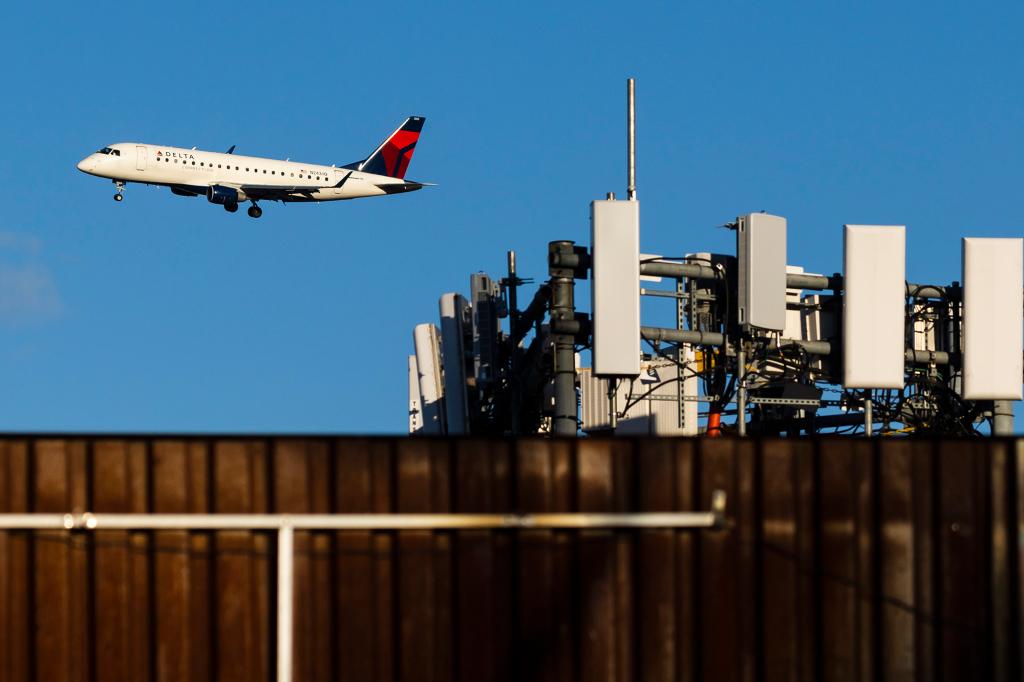 A Delta airlines airplane on approach to land at LaGuardia Airport passes telecommunications antennae on a rooftop in Queens.