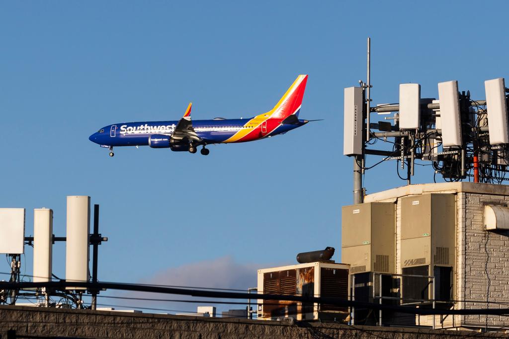 A Southwest Airlines airplane on approach to land at LaGuardia Airport passes telecommunications antennae on a rooftop in Queens.